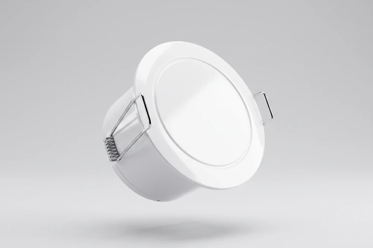 Angled view of a round white Room Occupancy Sensor with mounting clips